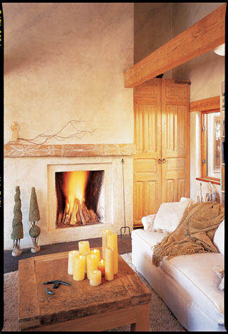 Bill, a sculptor who once owned a gallery in Aspen, Colorado, has added fanciful touches such as the windmill on the home’s roof, facing page. The front door, left, and the tall interior doors and the fireplace mantel, this page, are from salvage yards in Santa Fe, New Mexico.